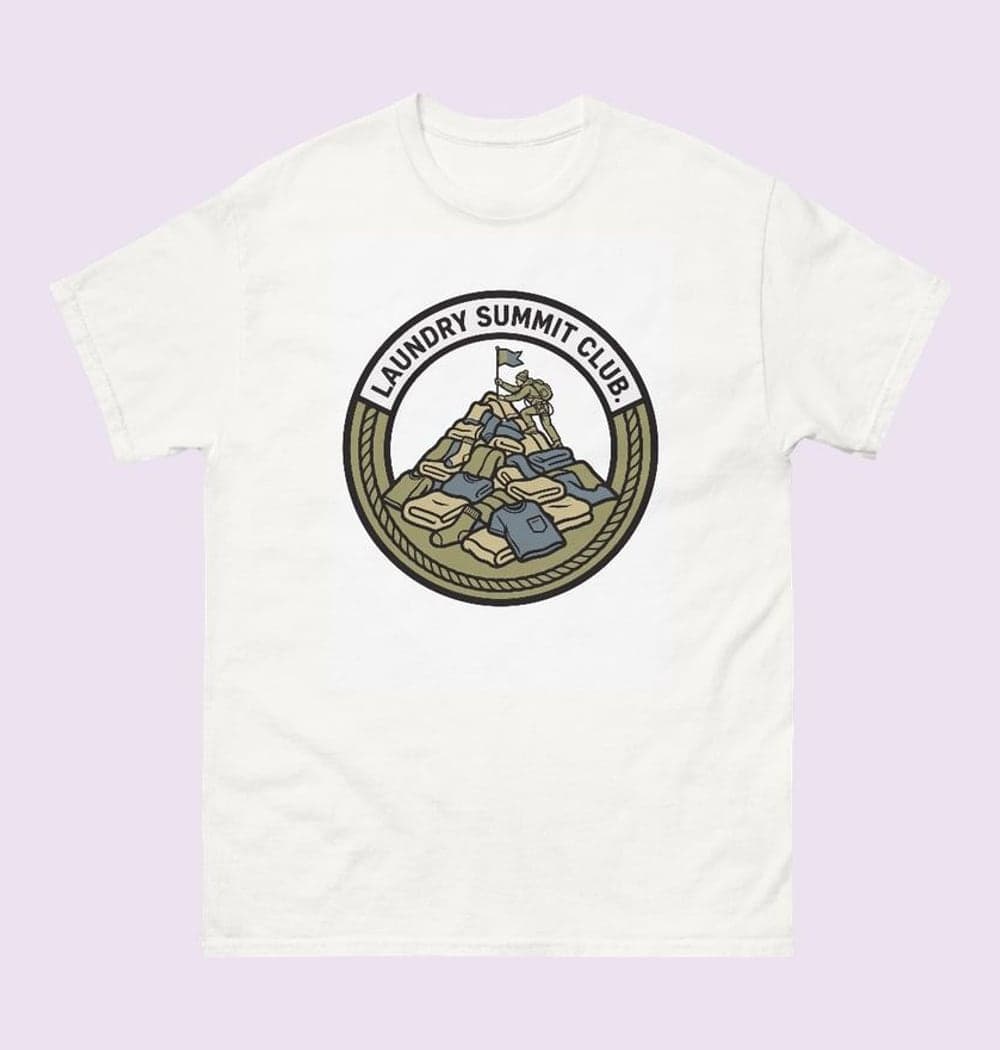 An original sports-style crest featuring a climber planting a flag atop a mountain of laundry, on a t-shirt (example made with AI)