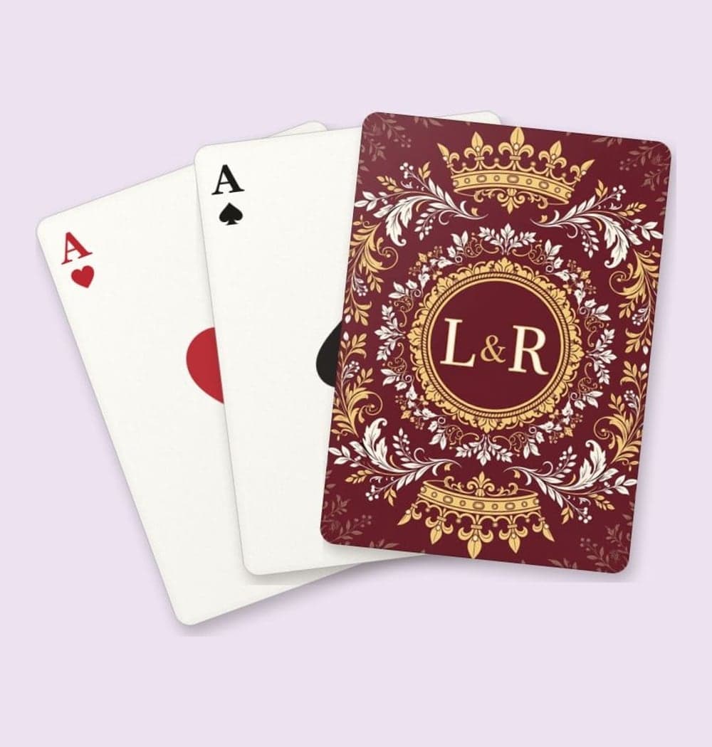 An original, rotationally symmetric fantasy crest with two mirrored crowns, decorative foliage, and the initials at the center, on playing cards (example made with AI)