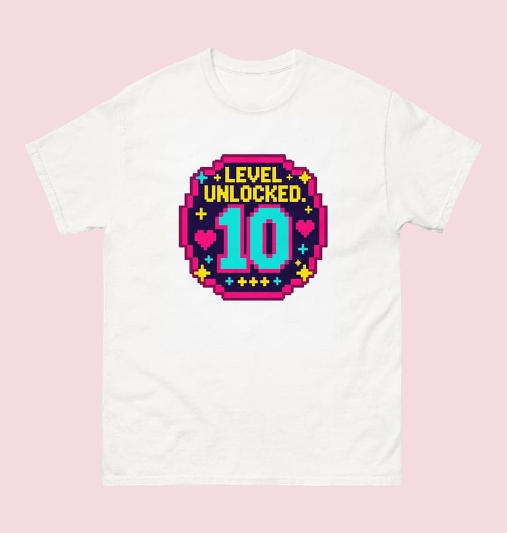 An original arcade-style birthday emblem with the supplied age as a large central number and the words “LEVEL UNLOCKED.” Add small stars, hearts, and geometric sparkles, on a t-shirt (example made with AI)